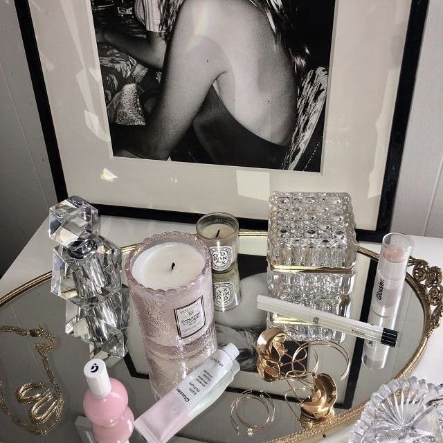 a glass table topped with lots of different types of cosmetics and perfume bottles on top of it