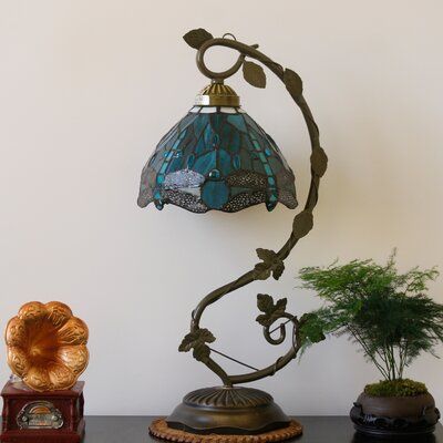 a lamp sitting on top of a table next to a potted plant