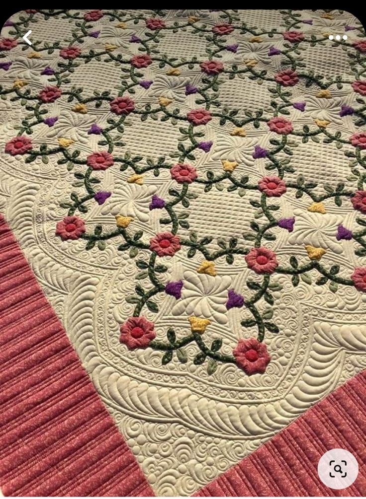 a quilted table runner with pink and yellow flowers on the center, along with a red border