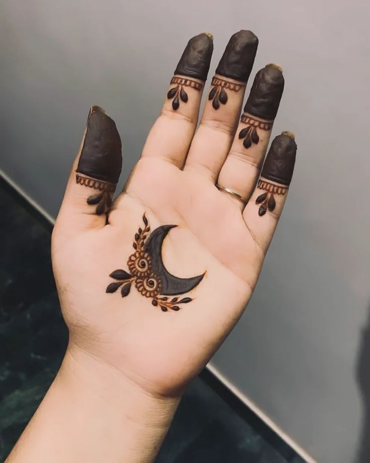 a woman's hand with tattoos on it and a crescent moon tattooed on the palm