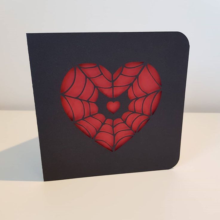 a card with a spider web heart cut out in the middle, on a table