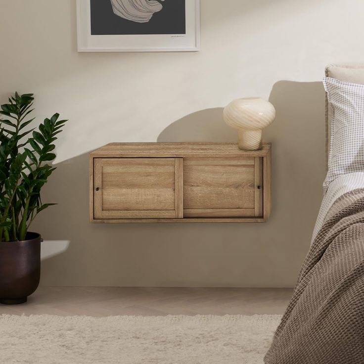 a bedroom with a bed, dresser and potted plant on the side table in front of it