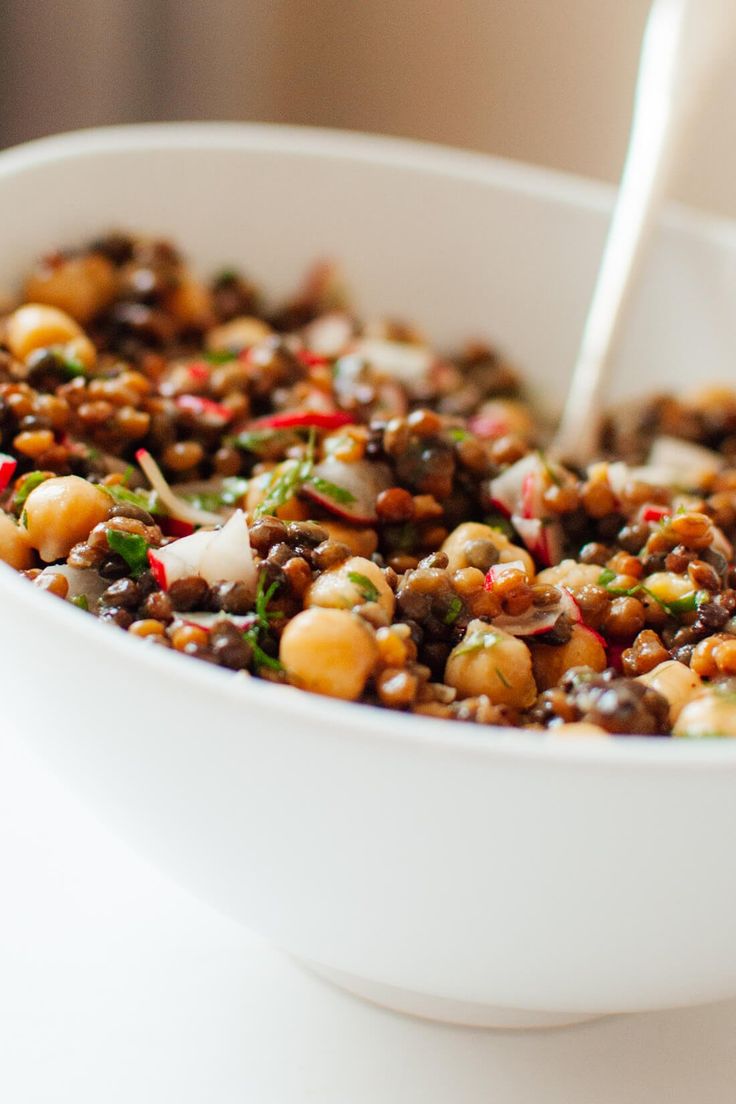 a white bowl filled with beans and other food on top of a table next to a pink frame