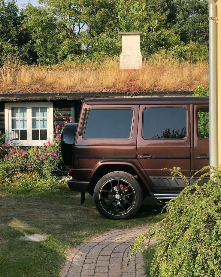 a brown jeep parked in front of a house with a green roof and grass on top