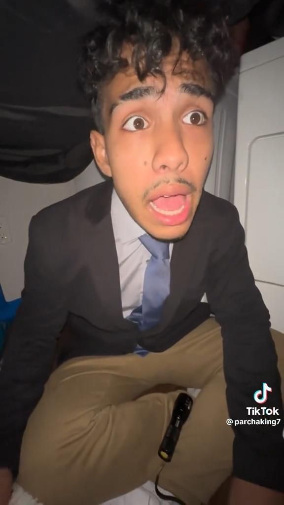 a young man in a suit and tie making a face with his mouth open while sitting on a plane