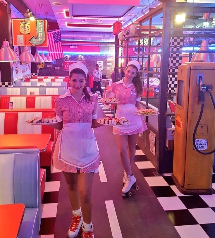 two girls in pink dresses are walking through a diner