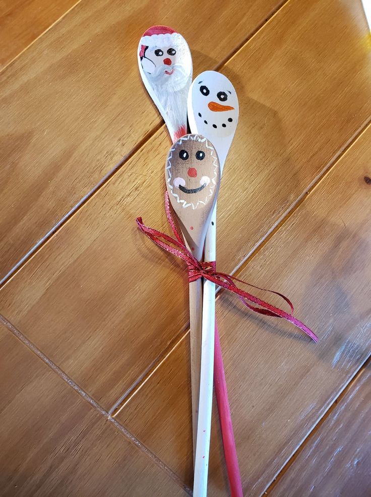 two spoons with faces on them sitting on a wooden floor next to each other