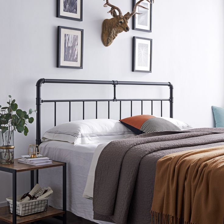 a bed with two deer heads mounted on the wall above it, and a side table next to it