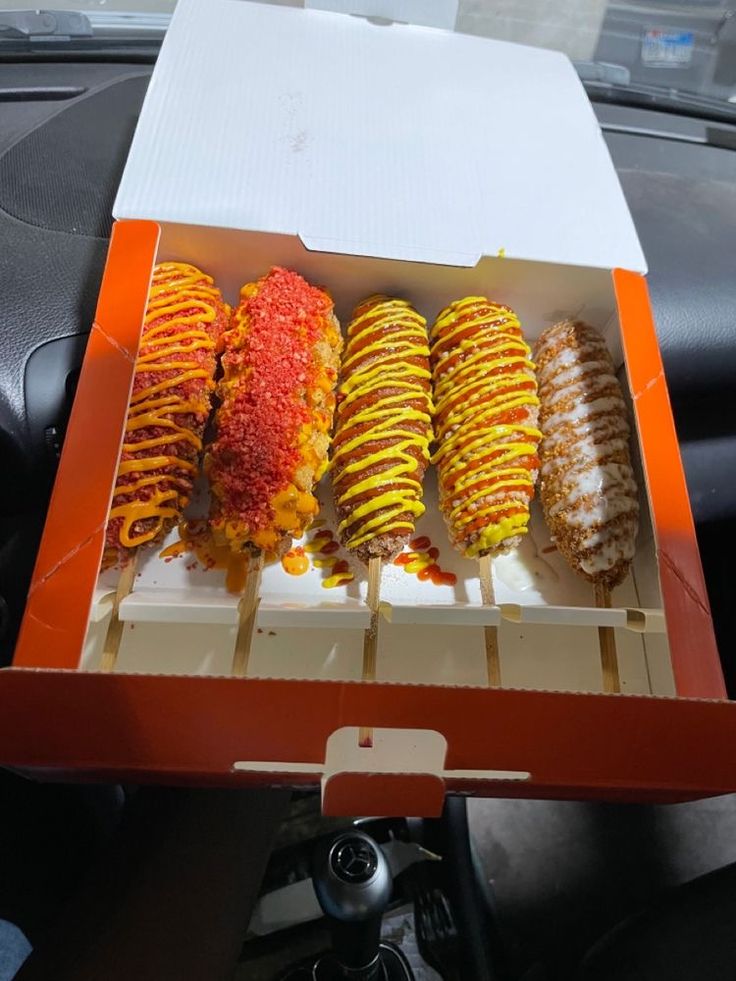 there are four different types of donuts in the box on the car dash board