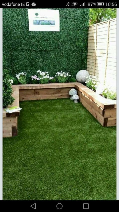 a small garden with grass and wooden benches