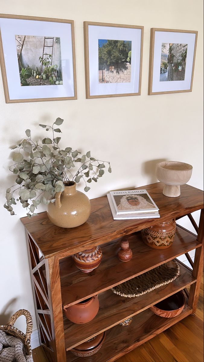 a wooden shelf with vases and pictures on the wall