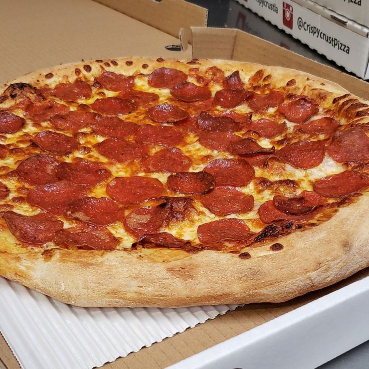 a pepperoni pizza sitting on top of a box