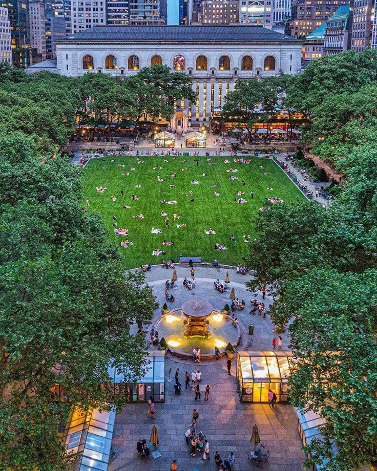 an aerial view of a park with lots of trees and people sitting on benches in the grass