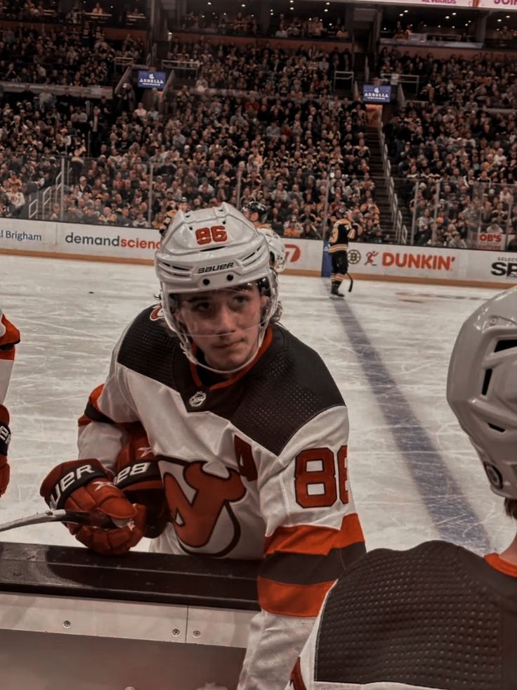 two hockey players sitting on the bench in front of an arena full of people watching