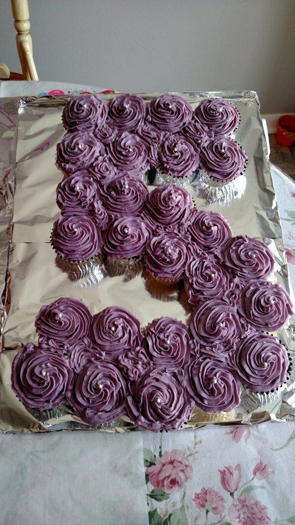 a sheet cake with purple frosting that has the letter e on it and is shaped like flowers