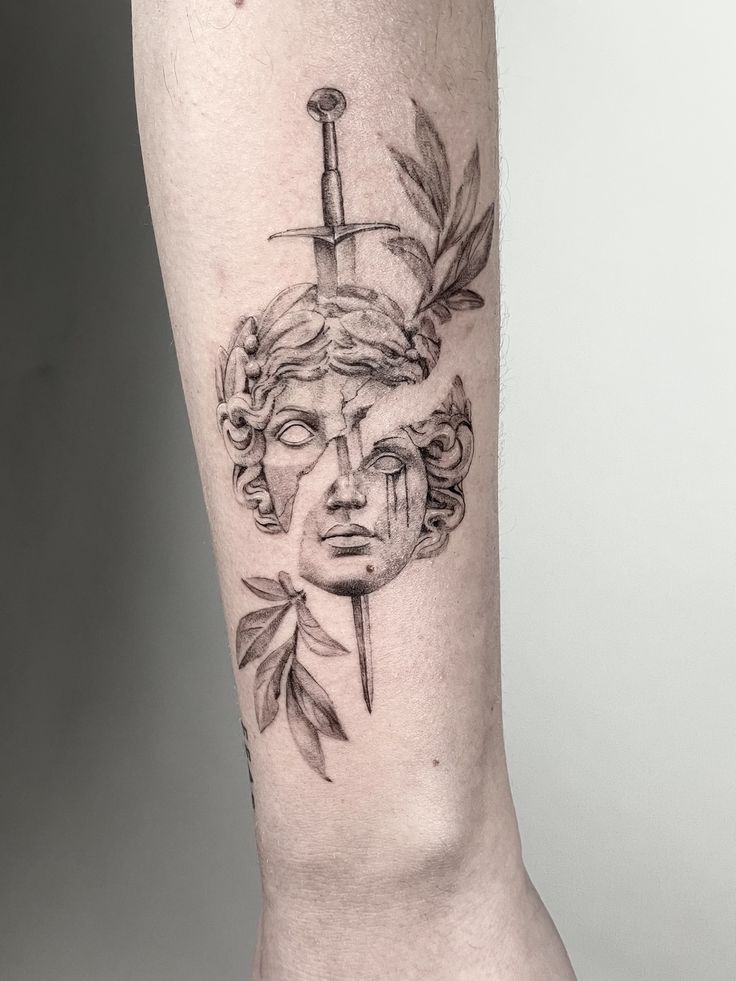 a tattoo on the leg of a person with a knife in her head and leaves around it