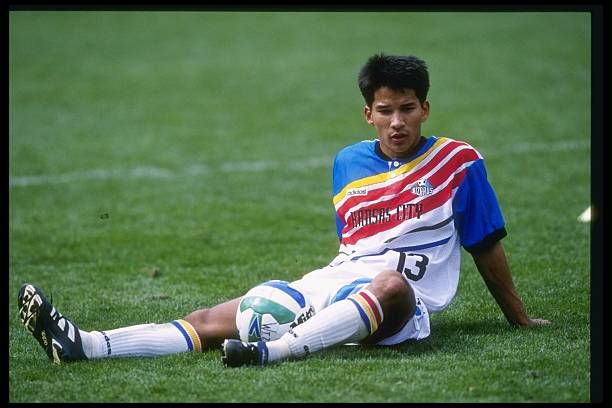 a young man sitting on the ground with a soccer ball