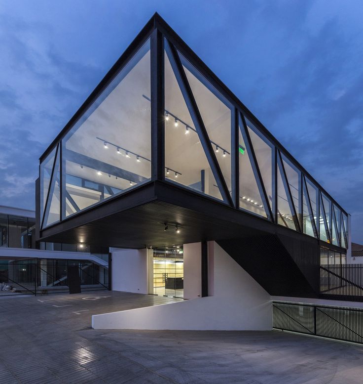 a modern building with glass and steel on the top floor is lit up at night