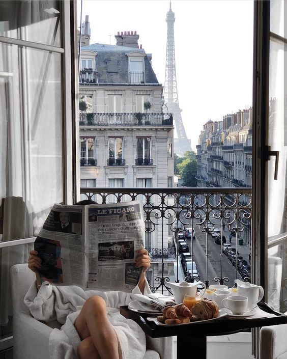 a person sitting on a couch reading a newspaper in front of the eiffel tower