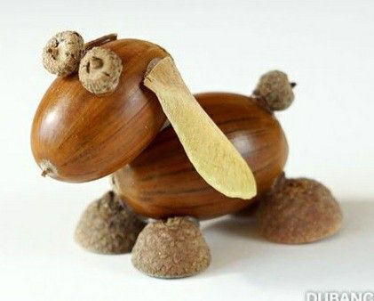 an animal made out of wood sitting on top of some rocks and nuts in it's mouth