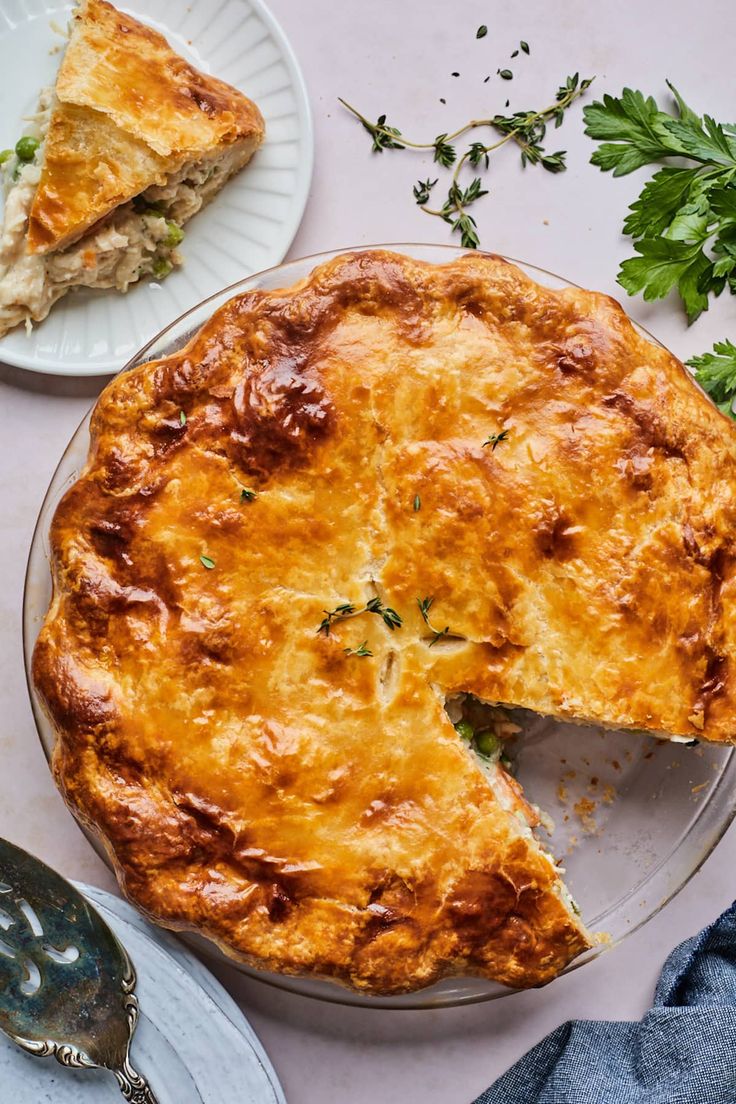 a pie on a plate with a slice missing from it next to a fork and knife