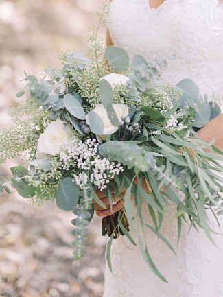 a bride holding a bouquet of flowers and greenery