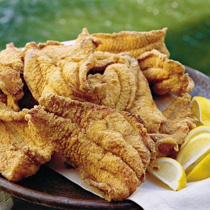 fried fish on a plate with lemon wedges