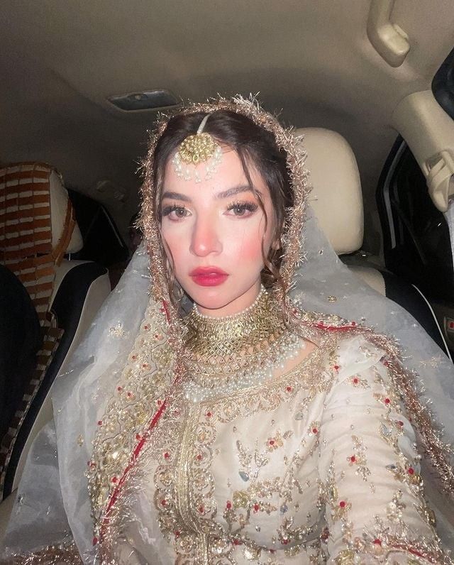 a woman in a car wearing a bridal gown and headpiece with veil on