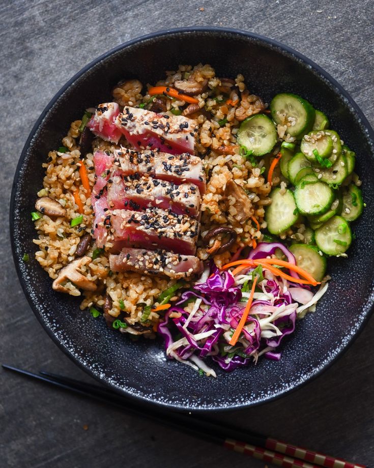 a black bowl filled with meat, rice and veggies