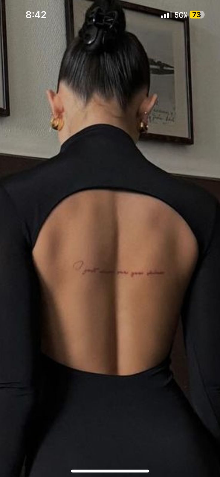 the back of a woman's black dress with her handwritten message on it