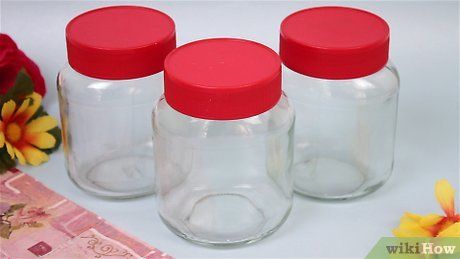 three empty glass jars with red lids are sitting on a table next to some flowers