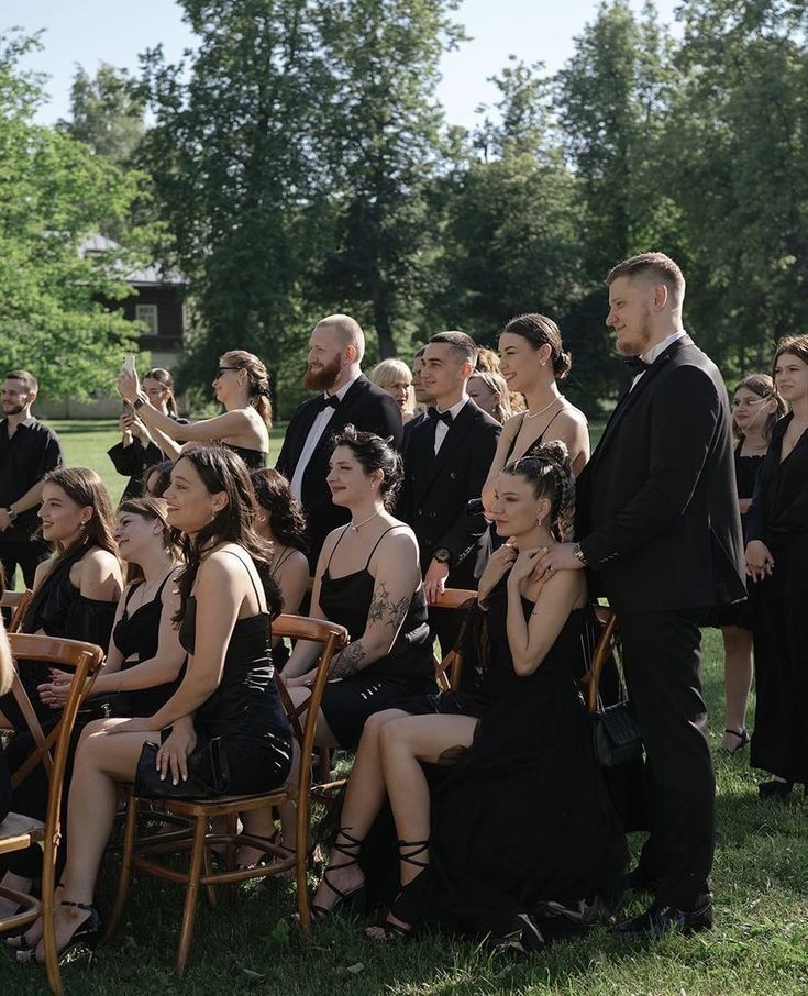 a group of people sitting on chairs in the grass with one person taking a photo