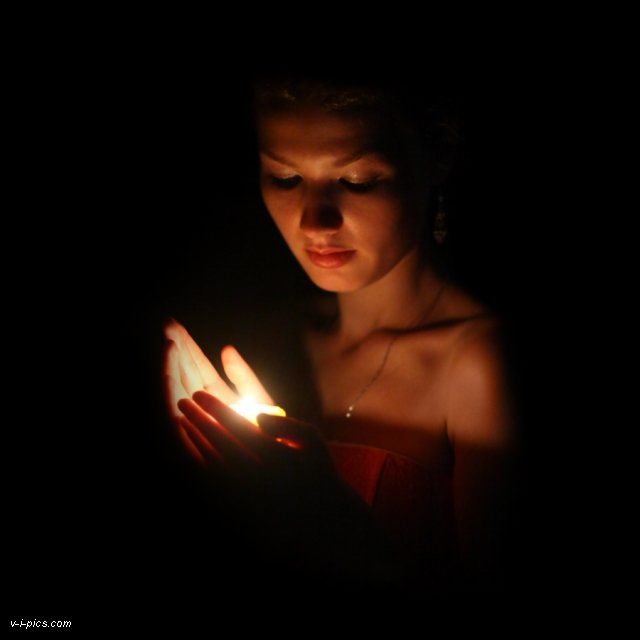 a woman holding a lit candle in her hands while looking down at the screen on her phone