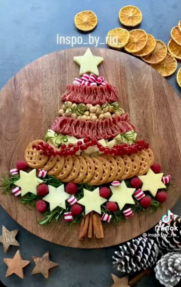 a christmas tree made out of crackers on a wooden platter surrounded by orange slices and pine cones