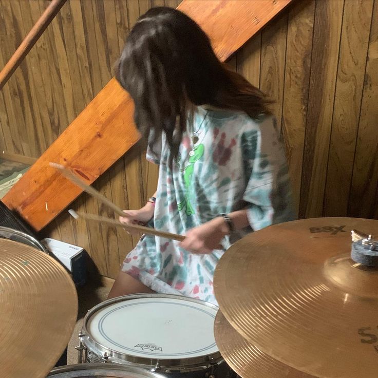 a woman is playing drums in front of some wood paneled walls and flooring