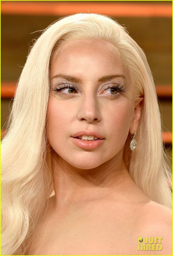 lady in white dress with blonde hair and diamond earrings posing for the camera next to another woman