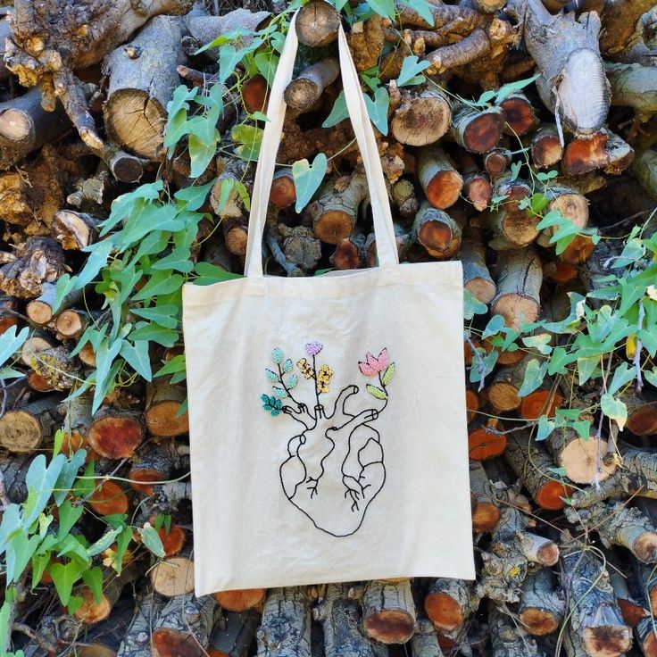 a tote bag sitting on top of a pile of logs next to some leaves