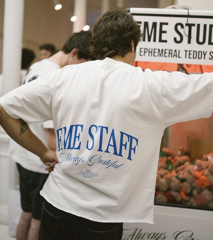 a man standing in front of a sign that says eme staff with his back to the camera