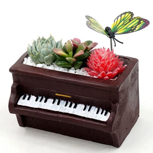 a planter with a butterfly sitting on top of it next to a piano keyboard