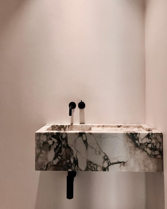 a bathroom with a marble sink and black faucet on the wall next to it