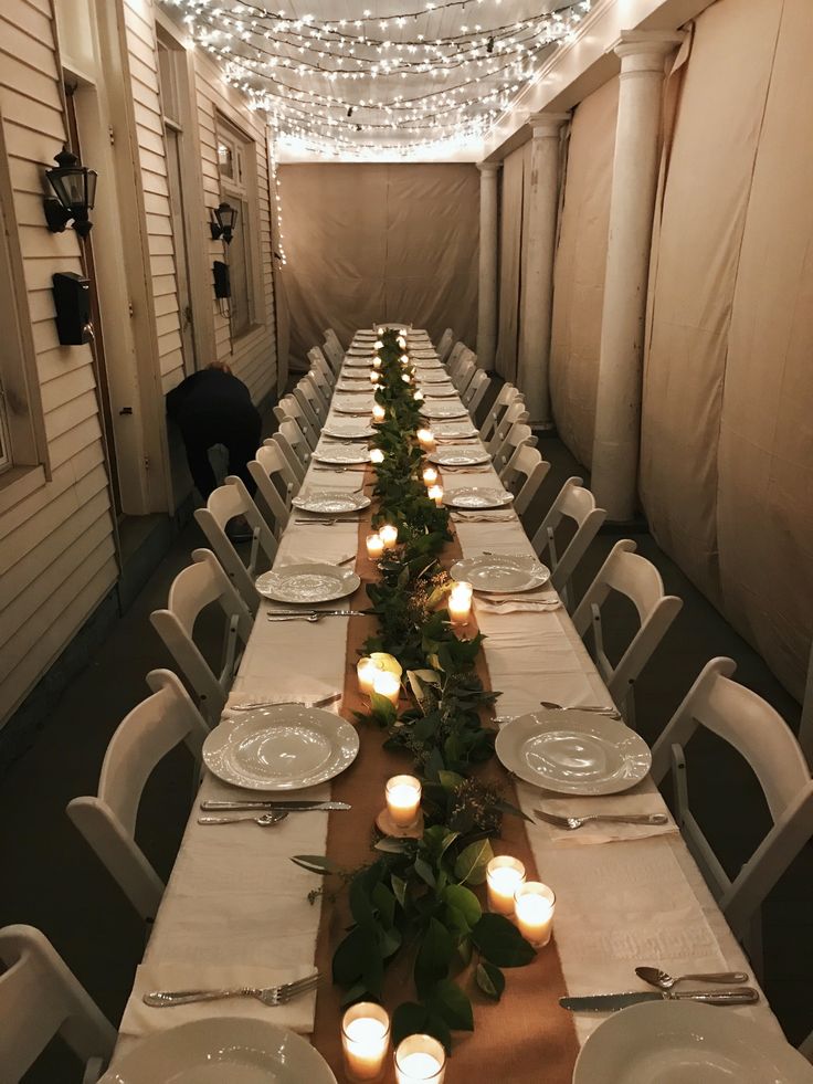 a long table is set up with candles and place settings for dinner guests to enjoy