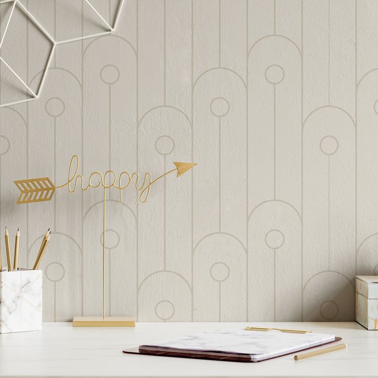 a desk with a notebook, pen holder and gold arrow on it that says happy