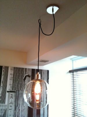 a light fixture hanging from the ceiling in a room with a large window behind it