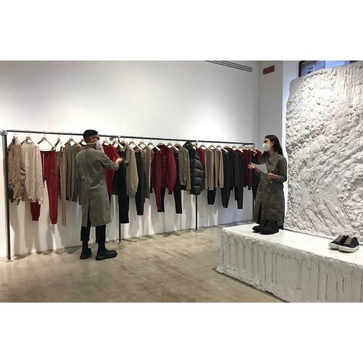 two people standing in front of a display of clothes