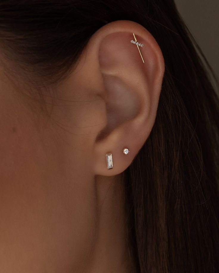 a close up of a person's ear with two piercings on top of it