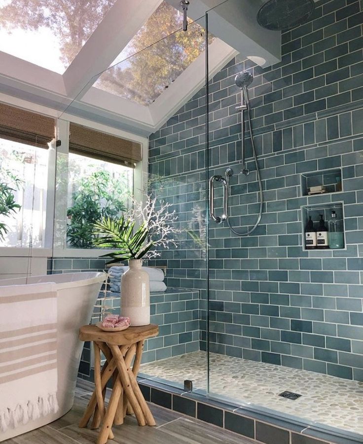 a bath room with a stand up shower next to a tub and a plant in a vase