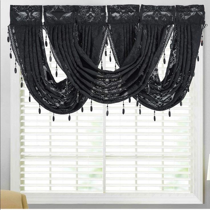 the curtains in this room are black and have fringes hanging from it's valance