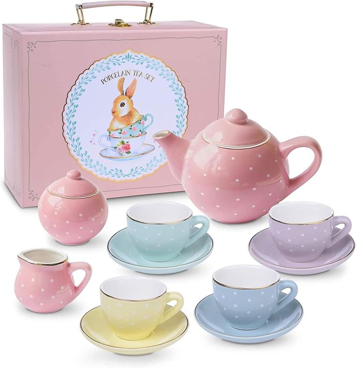 a tea set with cups and saucers in front of a pink box on a white background