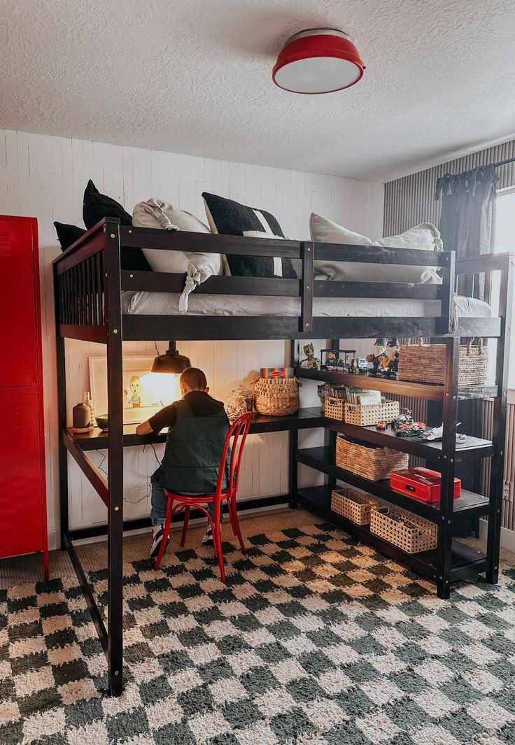 a person sitting at a desk in front of a bunk bed with two ladders