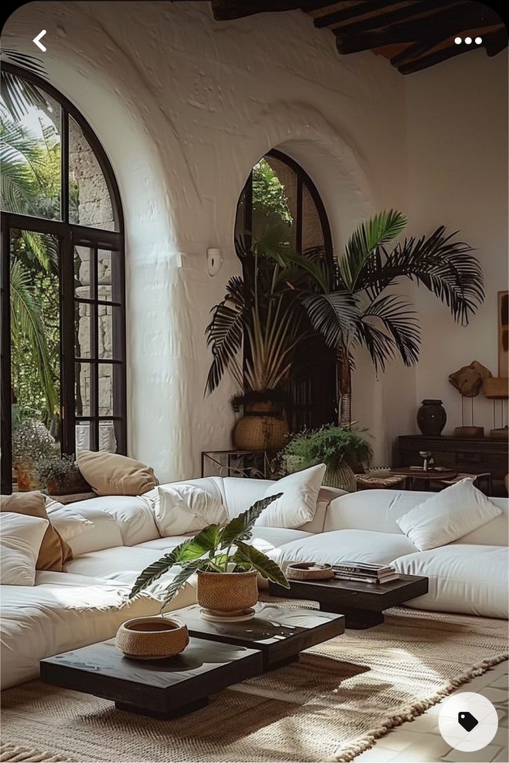 a living room filled with lots of white couches and pillows on top of a rug